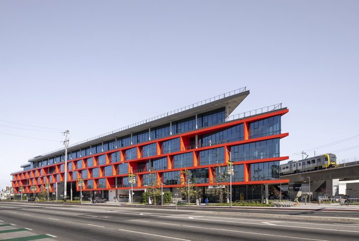 The Ivy Station office building in Culver City — WarnerMedia's building — with its red sawtooth façade beside the Metro E Line