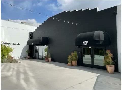 909 N. Orange exterior — the dark charcoal building with a stepped parapet and black NSF awnings over its glass entry doors, the white 925 N. Orange building beside it