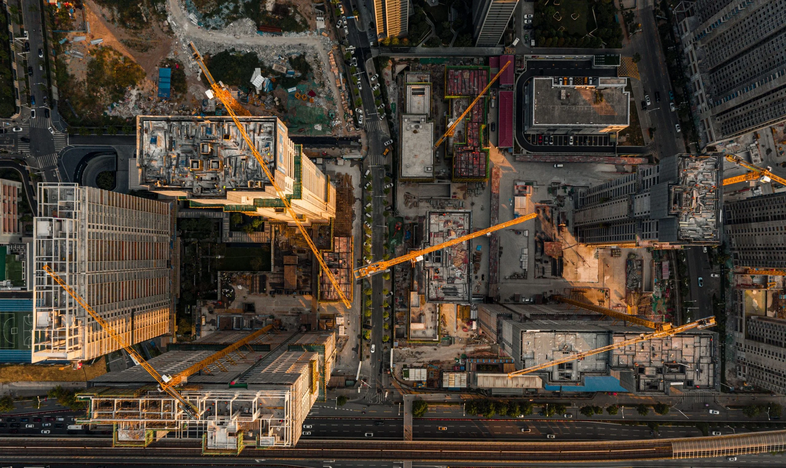Aerial plan view of a city district under construction — tower cranes over buildings rising
